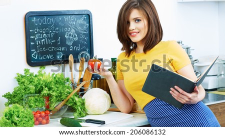 Woman in kitchen reed menu and cooking vegetarian food.