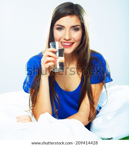 Young Woman in bed holding water glass. Smiling model.