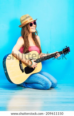 Music woman portrait with guitar. Blue background.