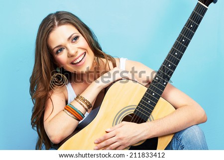 young model girl with acoustic guitar against blue wall background