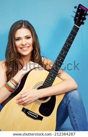 beautiful woman music portrait with guitar . blue wall background .