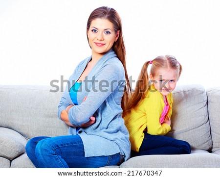 Woman with girl seating on sofa back to back. Relationship portrait.