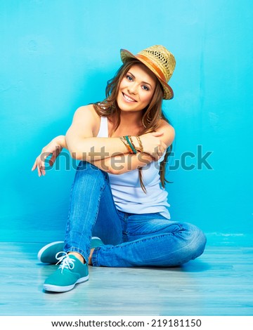 happy woman full body portrait . girl sitting on a floor in teenager style .  crossed leg
