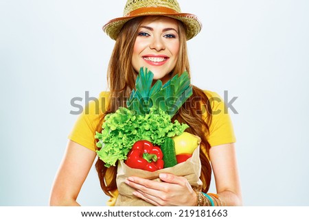 smiling woman holding paper bag with green vegan food . yellow hat . white background .