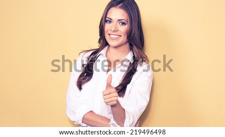 smiling business woman portrait. thumb up . white shirt. yellow background.