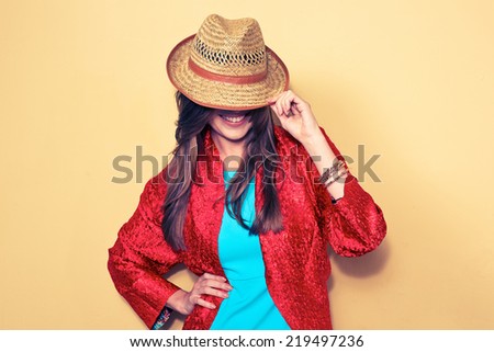 woman hides face behind a hat. fashion style portrait. blue dress. red cape.