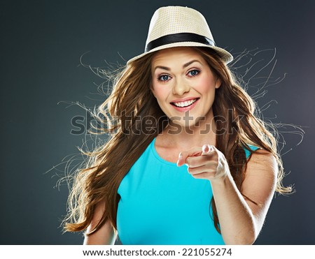 fashion style portrait of young smiling woman points a finger at the camera.  long waving hair