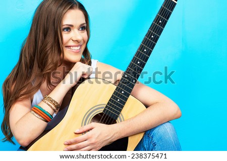 beautiful girl with guitar against blue background . long hair .