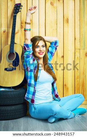 Hipster style portrait of smiling girl sitting on a floor. Acoustic guitar. Hippie style.