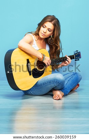 beautiful woman music portrait with guitar . blue wall background .