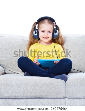 Girl sitting on sofa with tablet. Child home education.