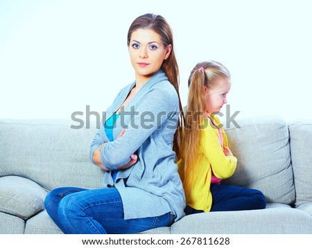 Mother with daughter seat on sofa back to back. Woman with girl portrait.
