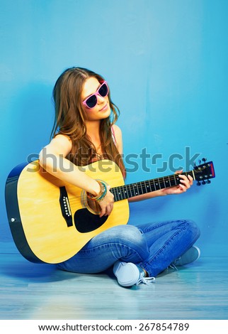 girl with guitar against blue . hipster style portrait of young woman .