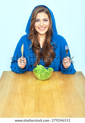 Portrait of smiling woman with diet vegetarian food. Young female model sitting at table.