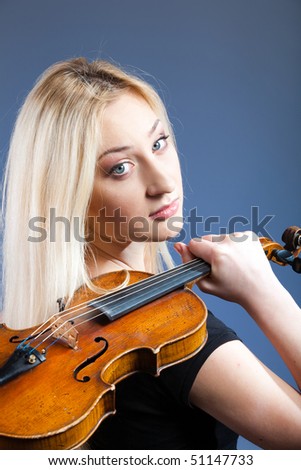 Young woman holding violin on the shoulder with his back and looks forward