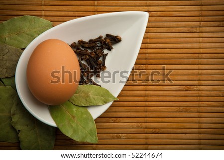 Egg and laurel leaves in a white container in the bamboo mat