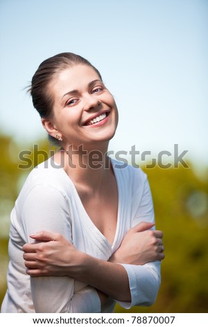 Woman on summer tree and sky background. Outdoor portrait with big smile.
