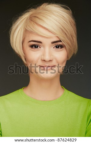 Young woman green dressed portrait. Closeup beauty studio shoot. Healthy clean skin and perfect makeup on beautiful face of white model with short blonde hair.