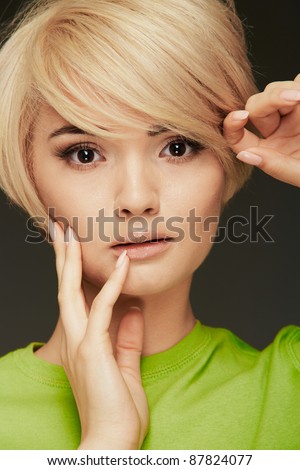 Young woman green dressed portrait. Closeup beauty studio shoot. Healthy clean skin and perfect makeup on beautiful face of white model with short blonde hair.