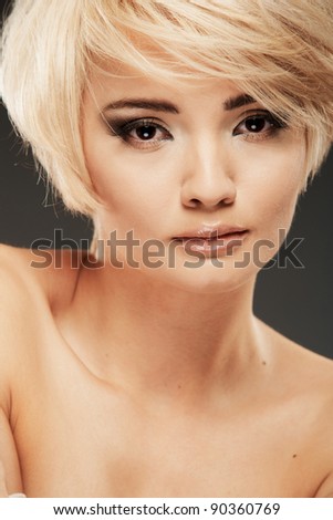 Young woman portrait. Closeup beauty studio shoot. Healthy clean skin and perfect makeup on beautiful face of white model with short blonde hair. Beautiful girl. Posing fashion model.