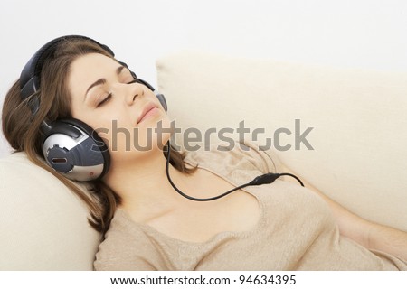 young girl portrait lying on a sofa, listen music in headphones. indoor relax at home. beautiful woman.