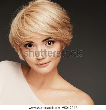 Young woman portrait. Closeup beauty studio shoot. Healthy clean skin and perfect makeup on beautiful face of white model with short blonde hair.