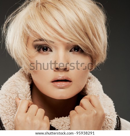 Young woman portrait. Closeup beauty studio shoot. Healthy clean skin and perfect makeup on beautiful face of white model with short blonde hair.