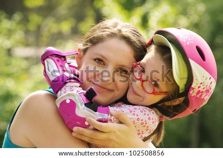 Outdoor portrait of caucasian mother and daughter wearing rollerblade protection and helmet.