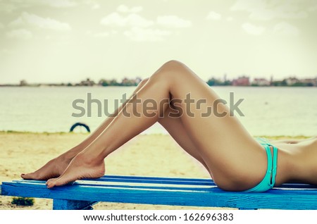 Attractive caucasian female legs on the bench at the beach.