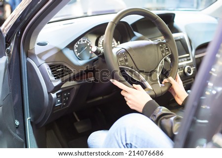 Hands holding a steering wheel of the modern car. Focus on hands