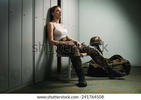 A shoot of young caucasian beautiful redhead woman sitting on the bench at locker room.