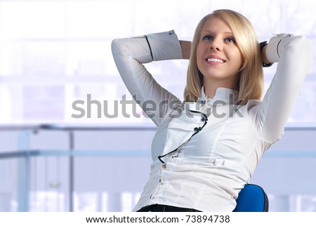 Young businesswoman relaxing in office, leaning on chair.