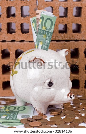 Piggy bank with euros, and bricks in the background