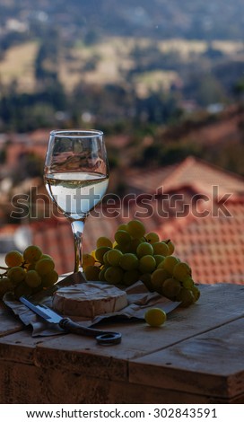 glass of wine on a background of mountains with cheese and grapes