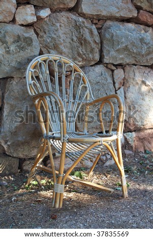 wicker chair beside a stone wall
