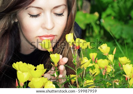 beautiful young woman smelling flowers