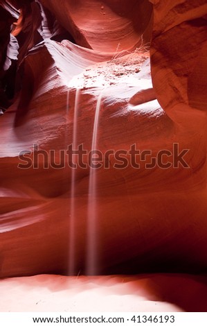 Light play with the stream of falling sand from the red rock of the Antelope Canyon