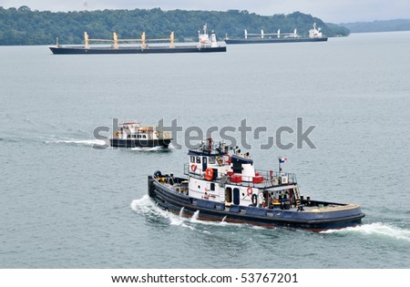Tugboat and Pilot boat in the Panama Channel with two cargo ships moving in the background