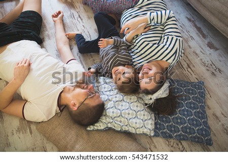 Happy pregnant mother, father and son Toddler lying on the floor, hugging,. Real interior, toning, lifestyle,casual style