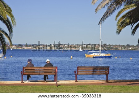 Elderly couple sitting by a river, framed with palm trees