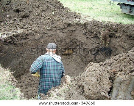 Construction worker digging a hole for a storm shelter