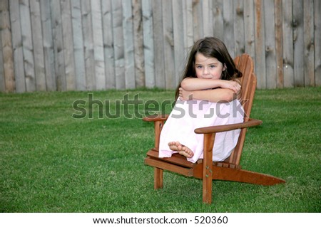 Little girl sitting alone in a chair in the backyard