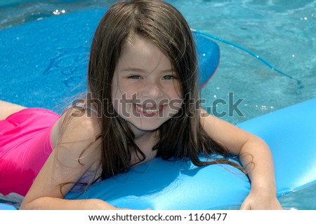 Little girl playing in backyard pool