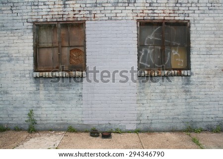 Two Rusted Metal Window Frames on Side of Brick Building