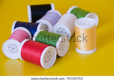 spools of colourful threads scattered on yellow surface