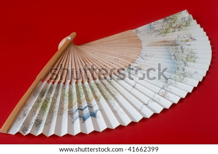 handmade bamboo Asian fan against red background