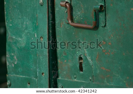 old green door with a  rusty handle and a key hole