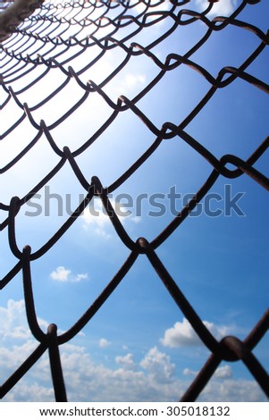 The metallic fence and a blue sky with white clouds.