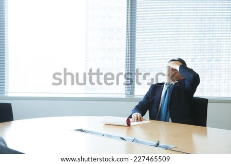 A business man covering his face in a office room