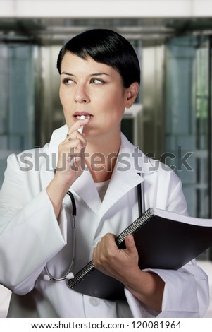 Thinking medical doctor with stethoscope. Over hospital background